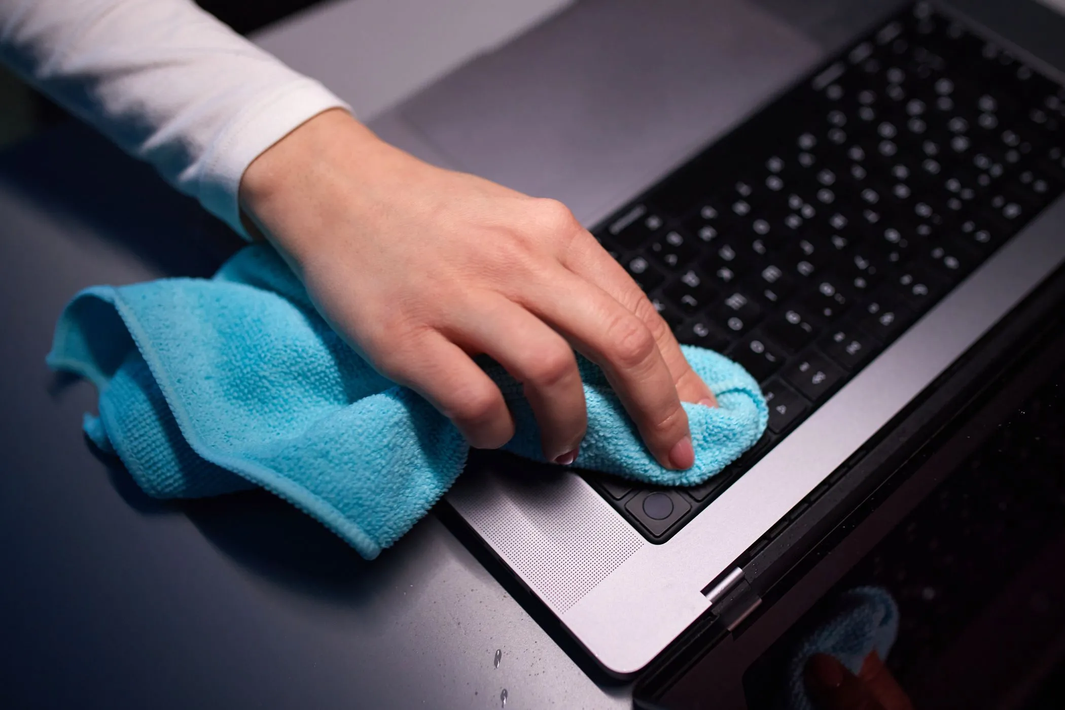 Người dùng đang vệ sinh màn hình MacBook bằng khăn microfiber.