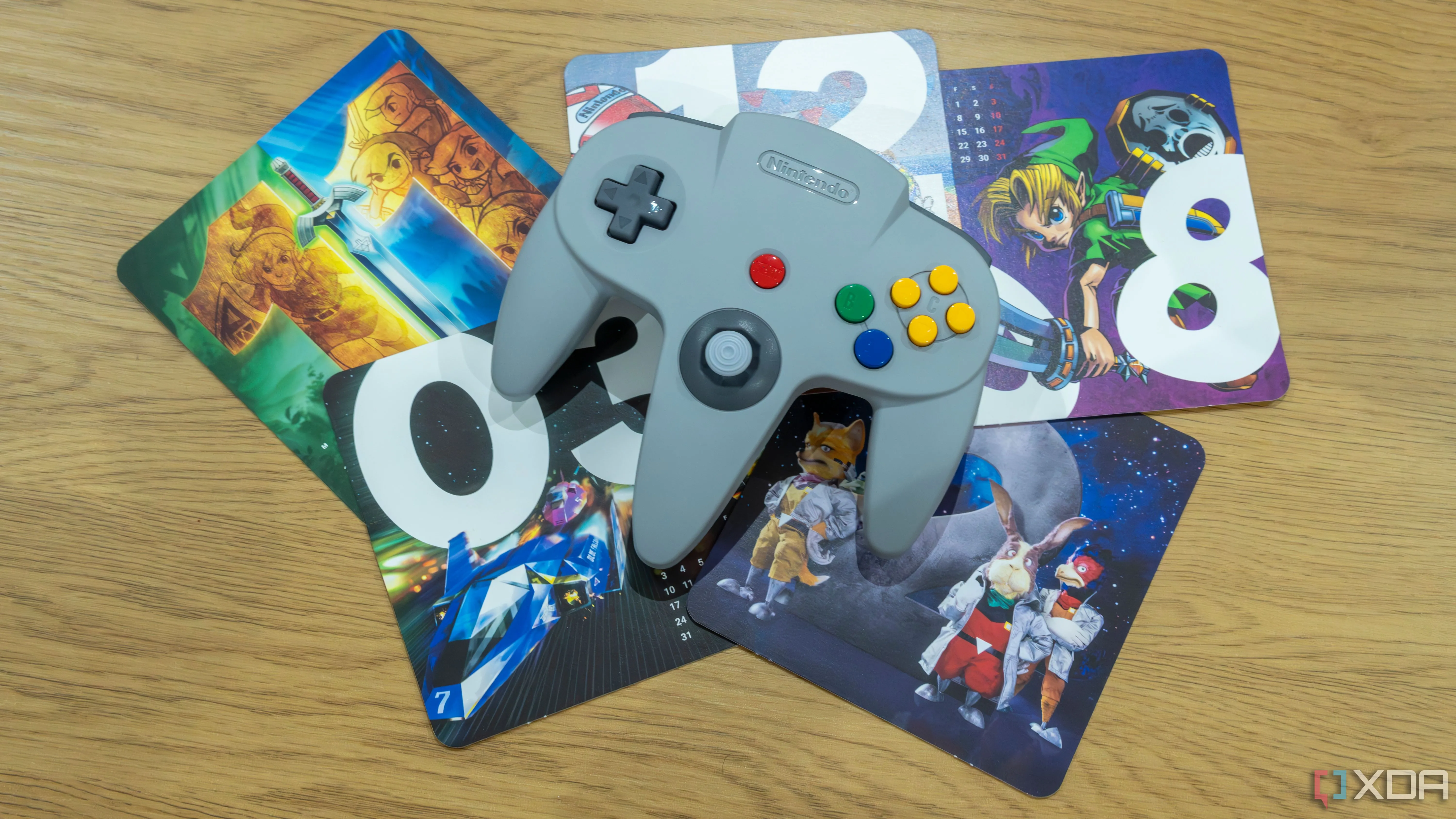 Tay cầm Nintendo 64 màu xám đặc trưng với hình ảnh các tựa game Nintendo 64 nổi tiếng hiển thị phía sau