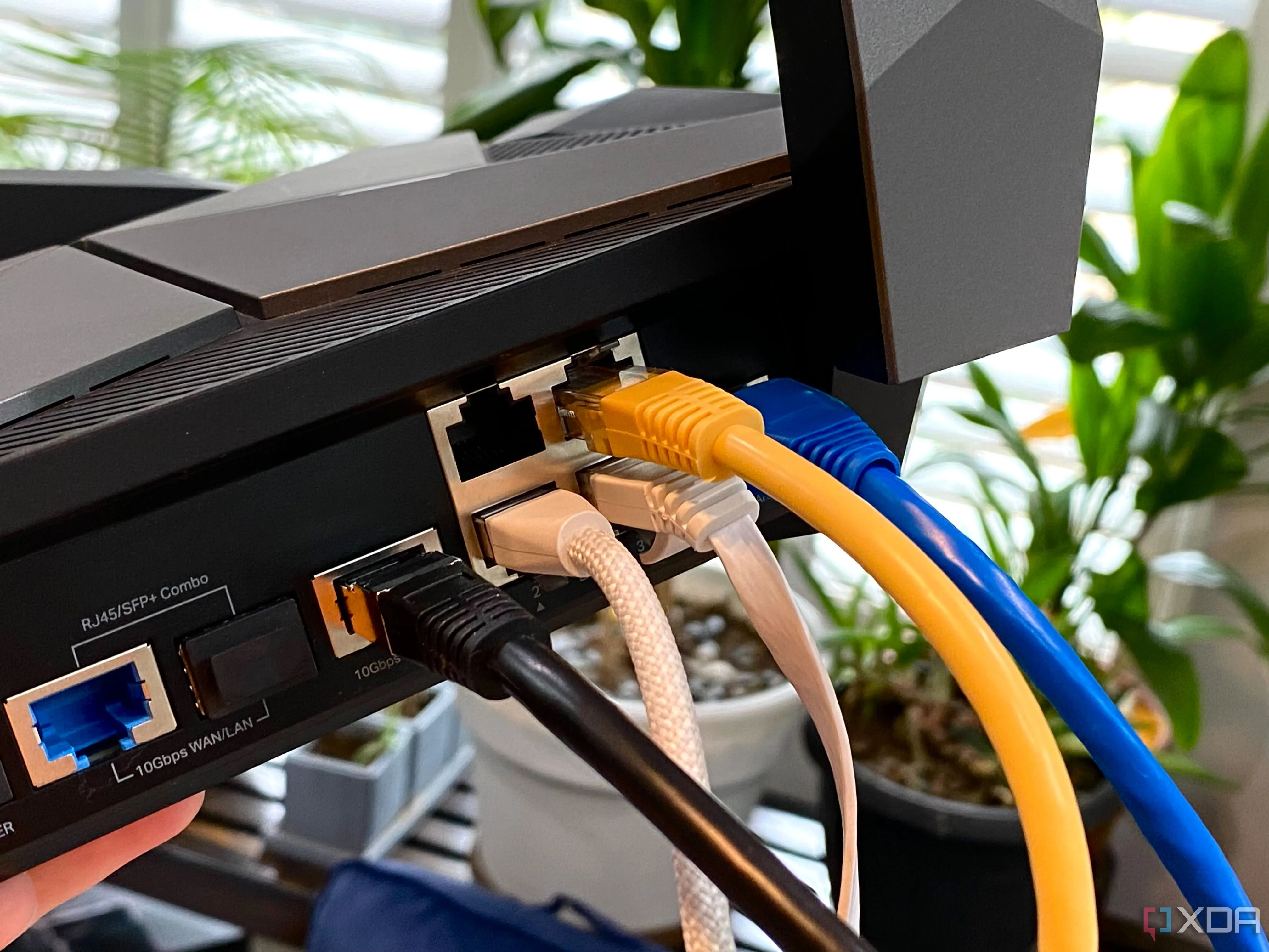 Bộ định tuyến TP-Link Archer AXE300 với nhiều cáp Ethernet nhiều màu sắc, minh họa cho hệ thống mạng phức tạp cần bảo mật.