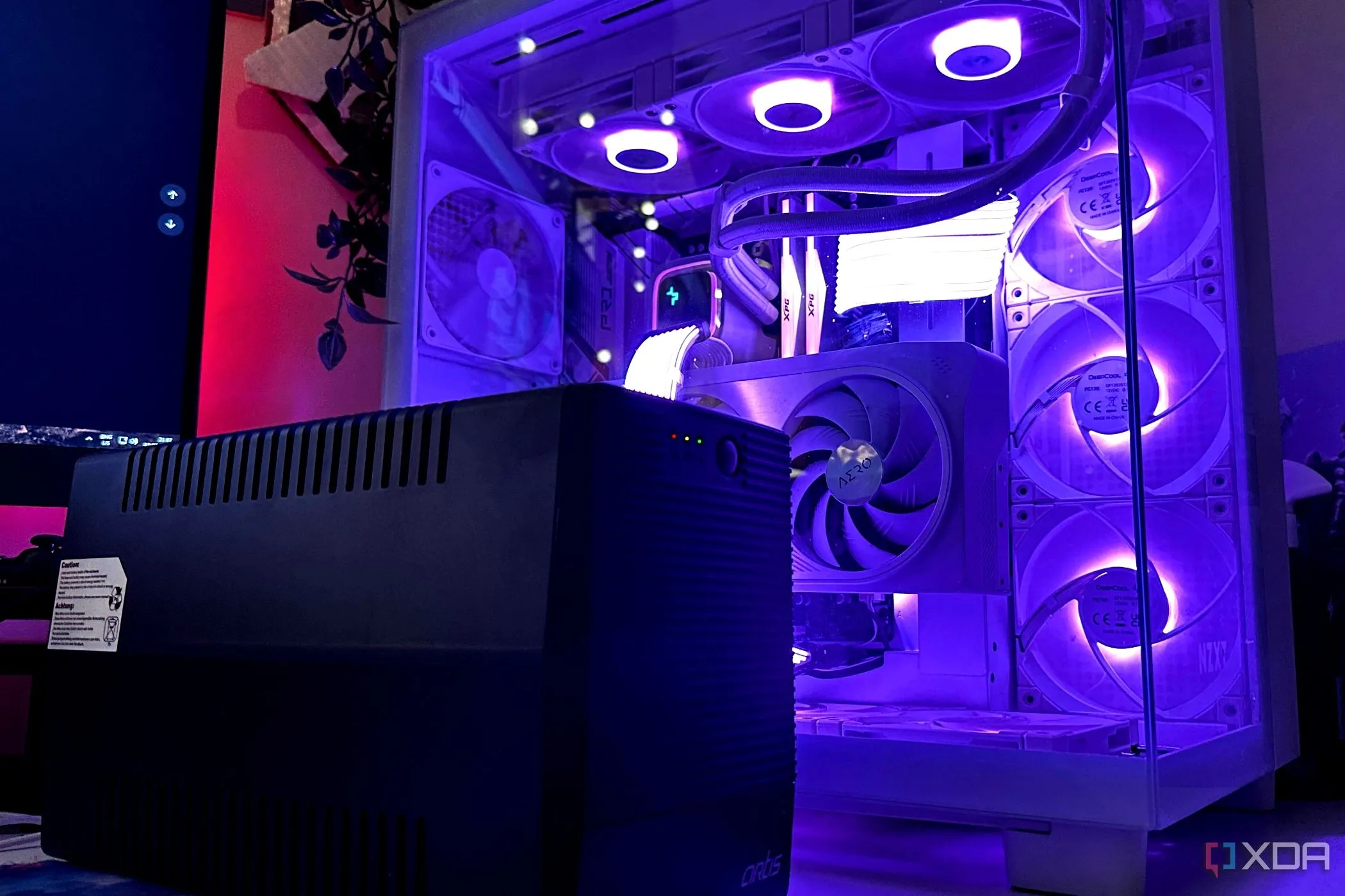 Bộ lưu điện UPS màu đen đặt cạnh thùng máy PC gaming, thiết bị bảo vệ cần thiết cho hệ thống