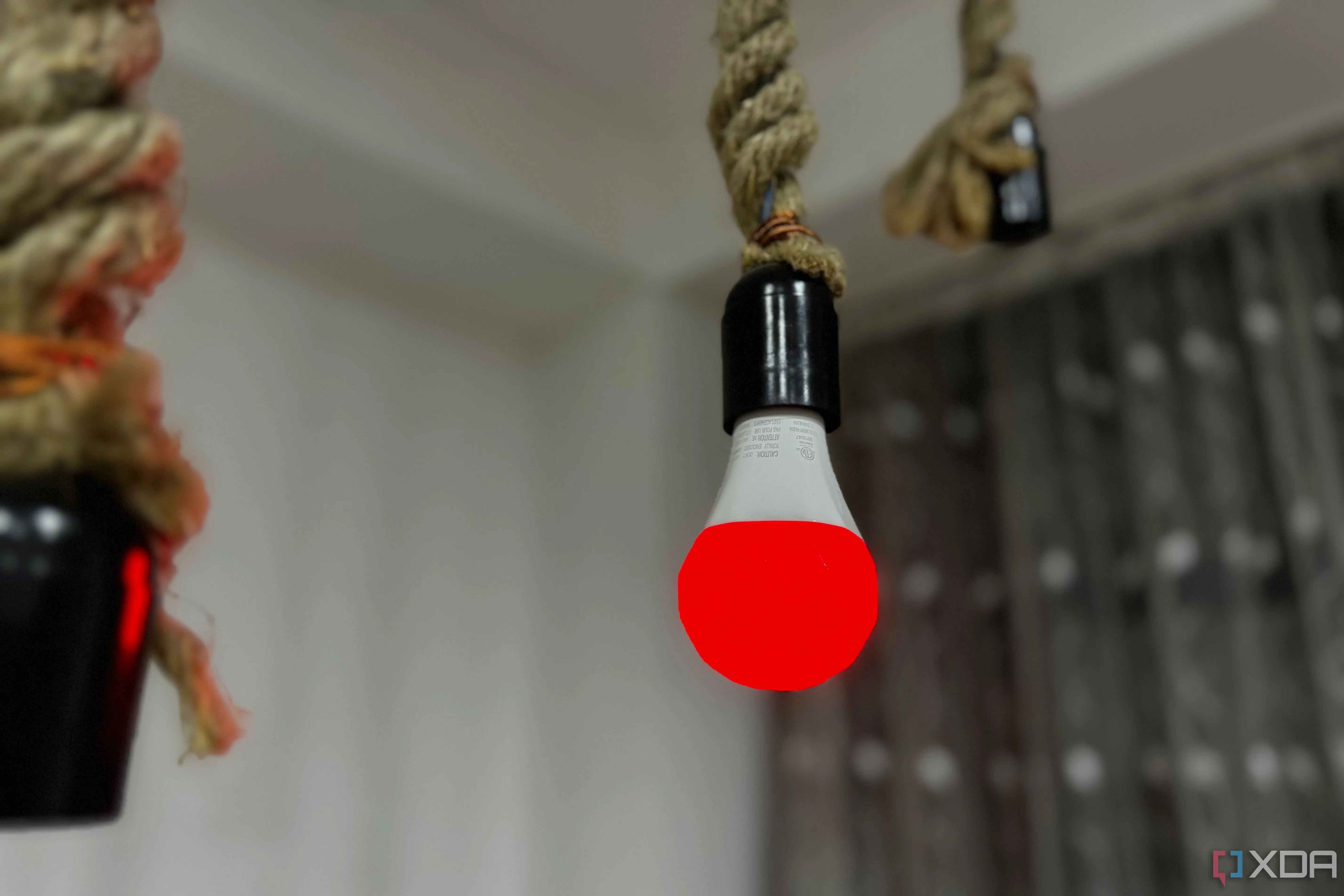 Bóng đèn thông minh Nanoleaf Essentials A19/E26 đang phát sáng màu đỏ, minh họa thiết bị IoT cần được bảo mật