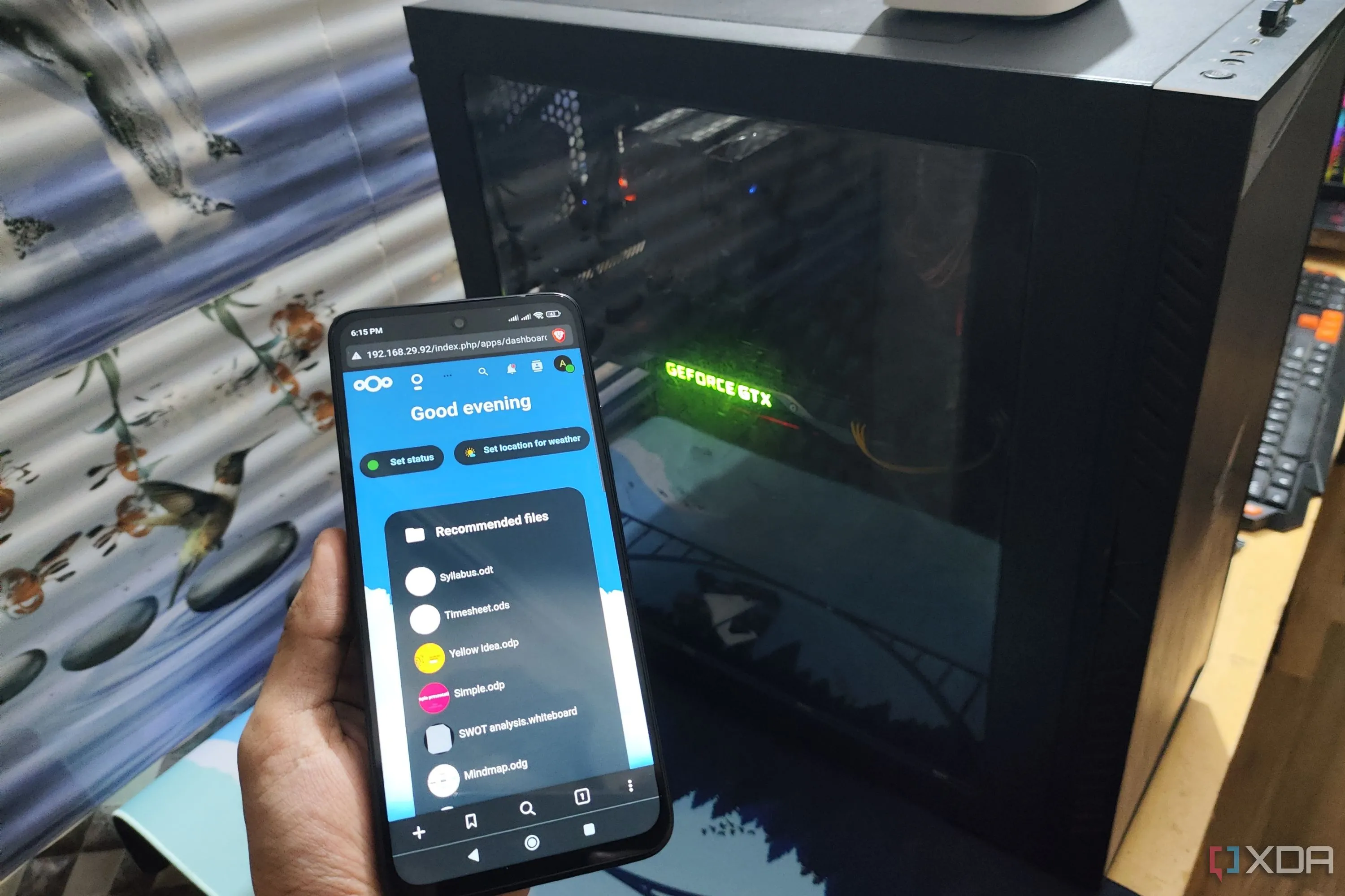 Giao diện Nextcloud hiển thị trên điện thoại Poco M6 Pro, với một máy tính để bàn ở phía sau