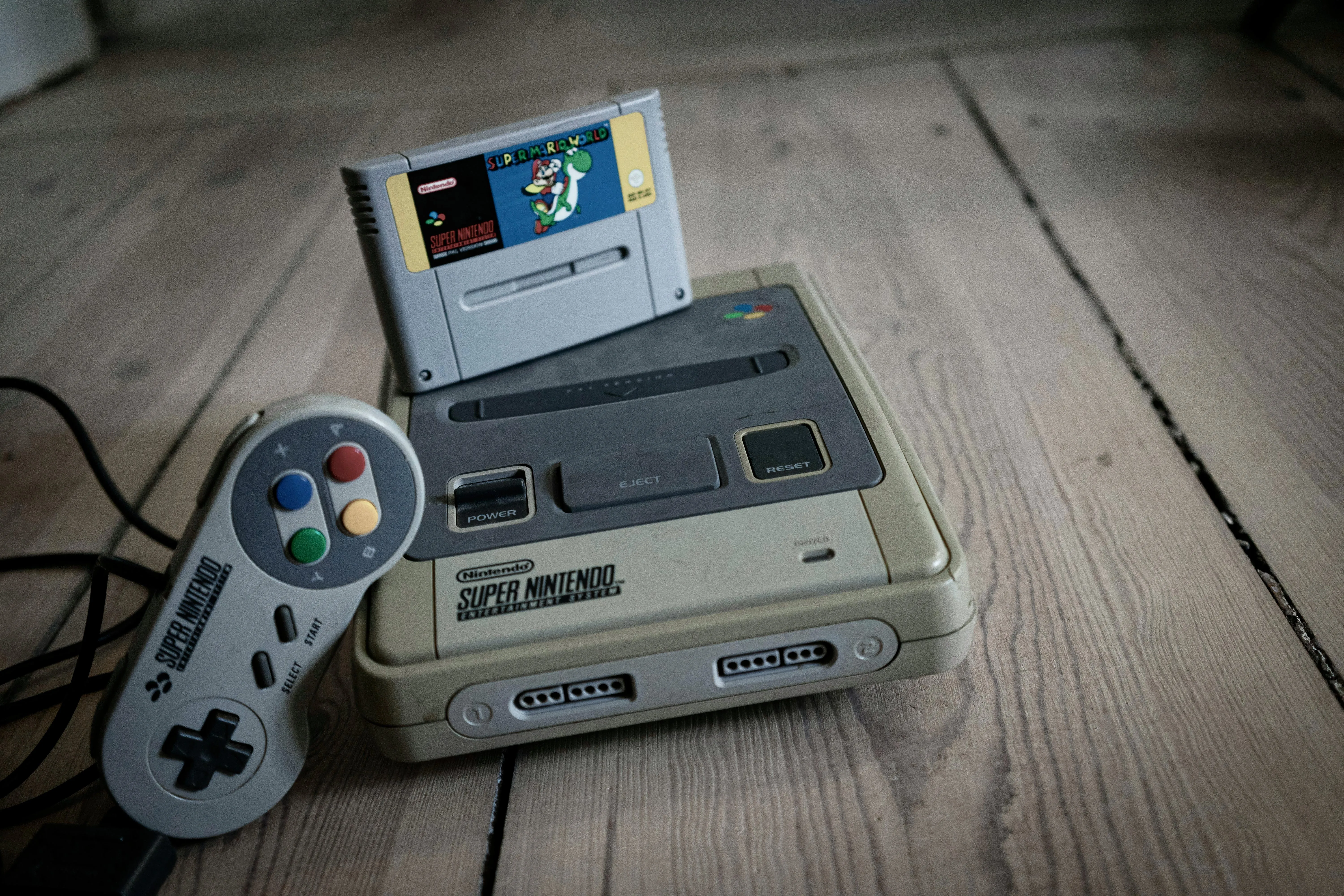 Hình ảnh hệ thống Super Nintendo Entertainment System (SNES) màu xám và tay cầm với các nút màu sắc đặc trưng