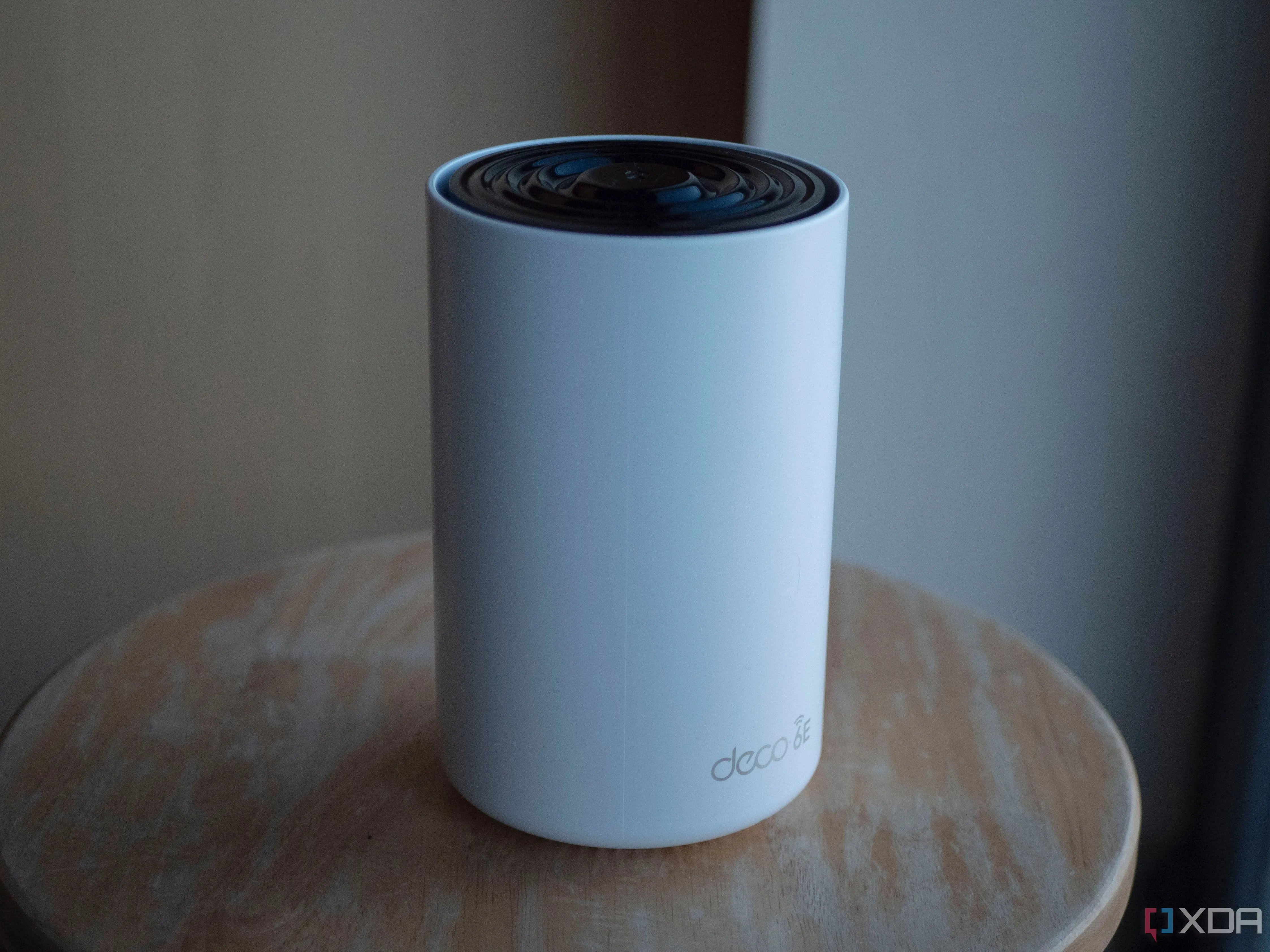 Hình ảnh một thiết bị TP-Link Deco XE75, một thành phần của hệ thống Wi-Fi Mesh hiện đại, đặt trên bàn làm việc.