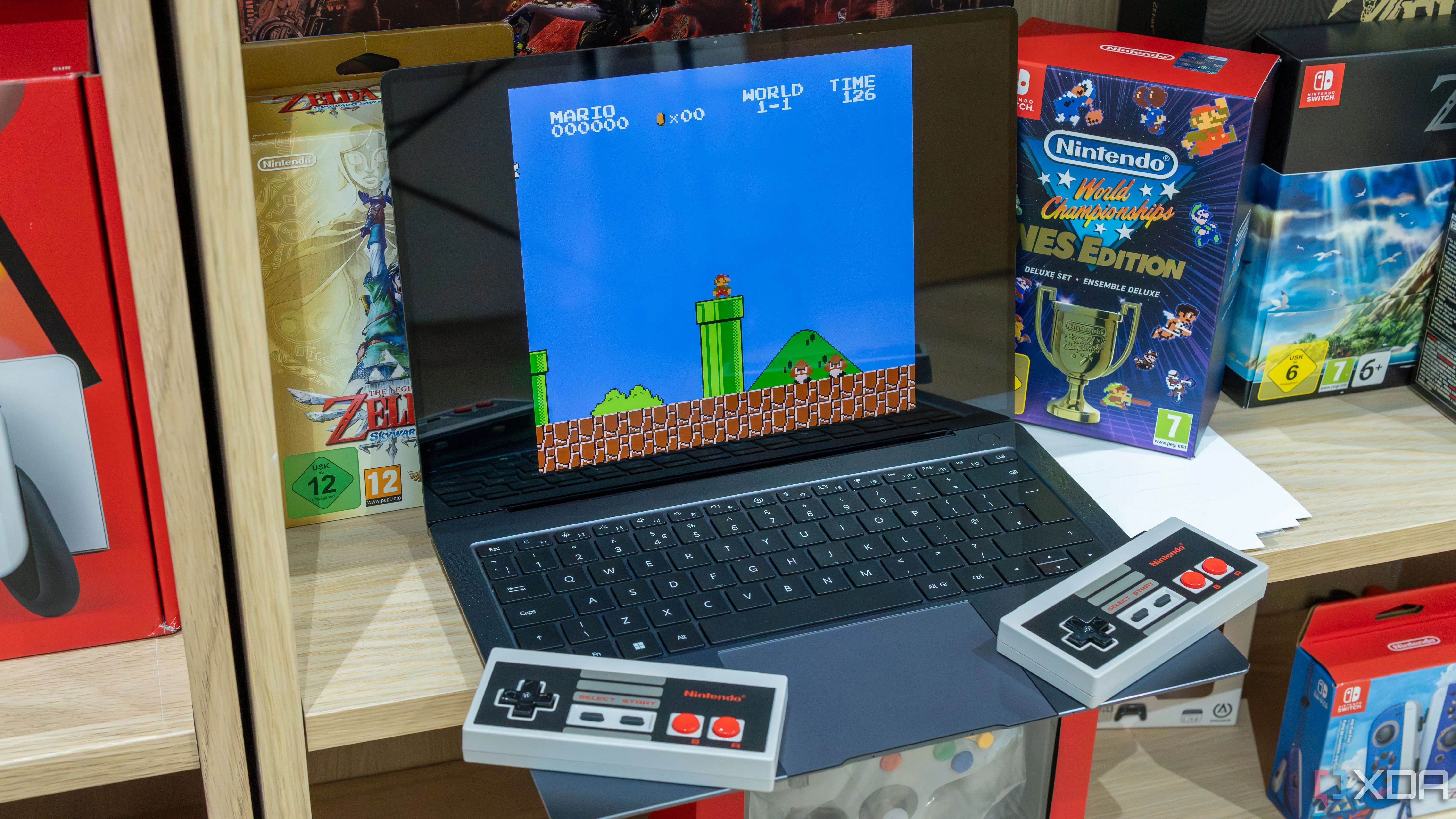 Laptop Windows 11 đang chạy game Super Mario Bros trên phần mềm giả lập, kèm hai tay cầm NES không dây.