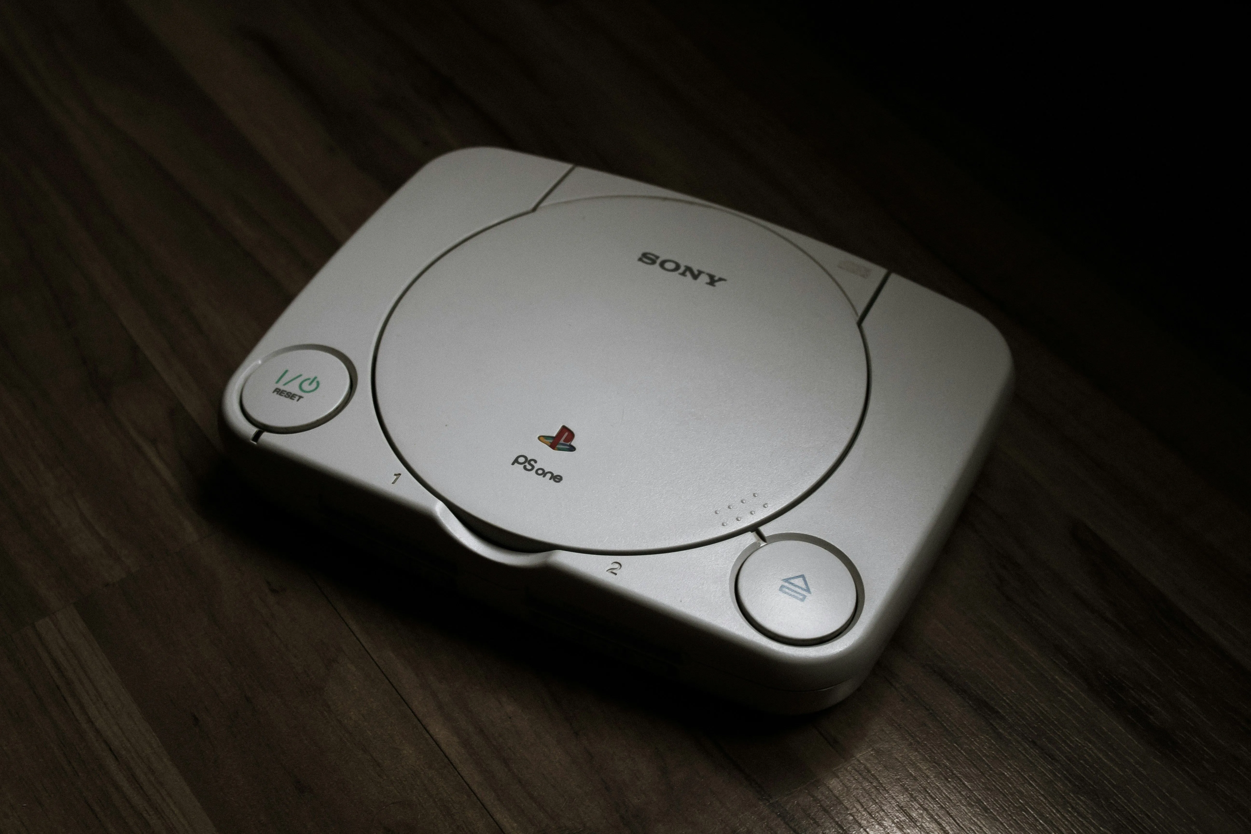 Máy chơi game PlayStation 1 trên nền gỗ, biểu tượng của kỷ nguyên gaming hiện đại
