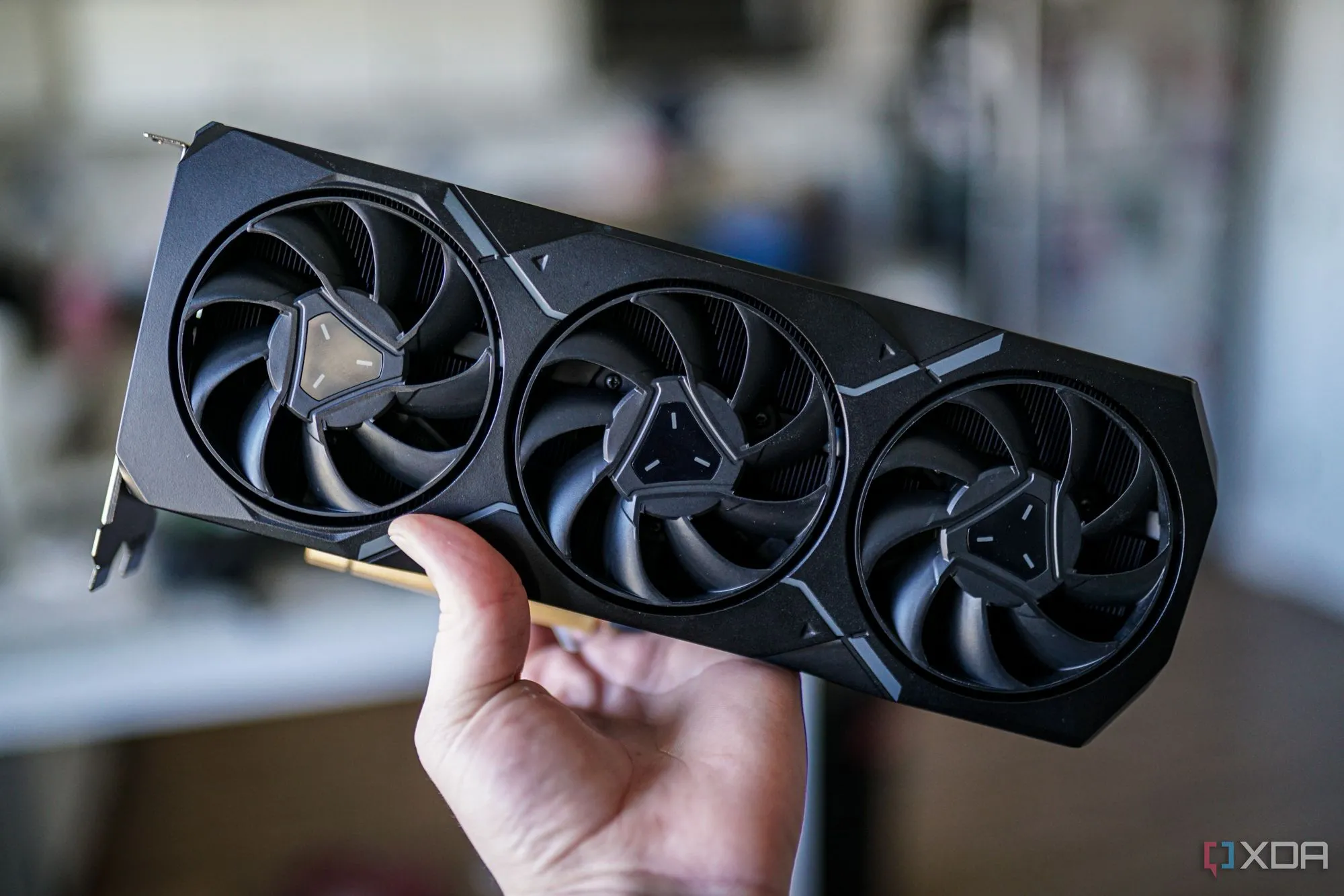 Một bàn tay đang cầm card đồ họa AMD Radeon RX 7900 XT, biểu tượng cho những nỗ lực tiếp theo của AMD trong cuộc đua công nghệ.