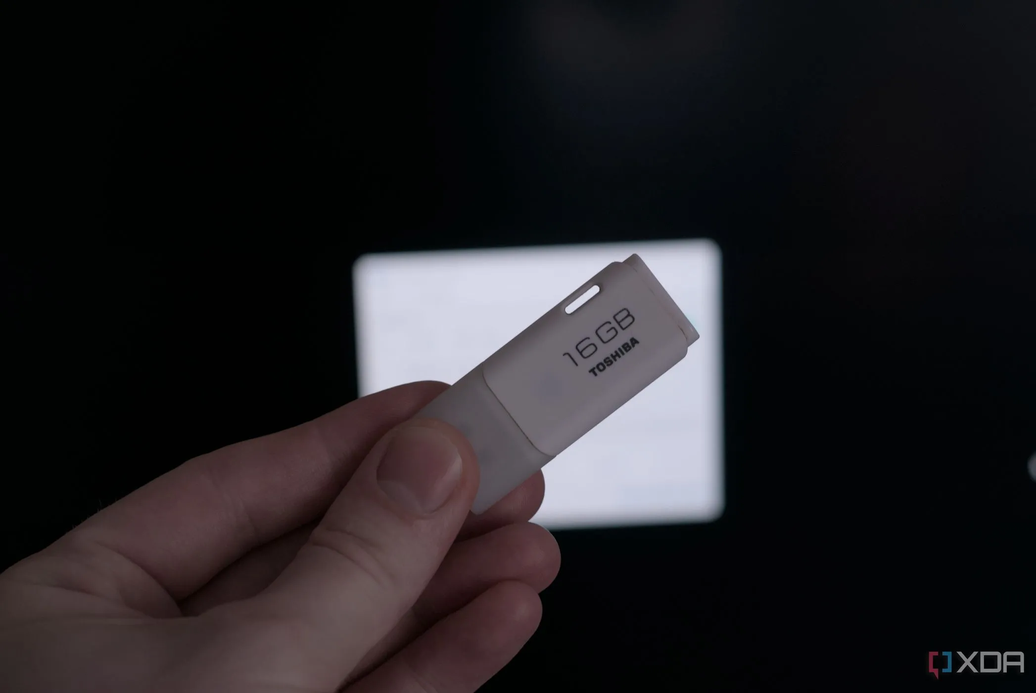 Một chiếc USB Flash Drive đang được cầm trên tay, biểu tượng cho nguy cơ tiềm ẩn từ thiết bị USB không rõ nguồn gốc.
