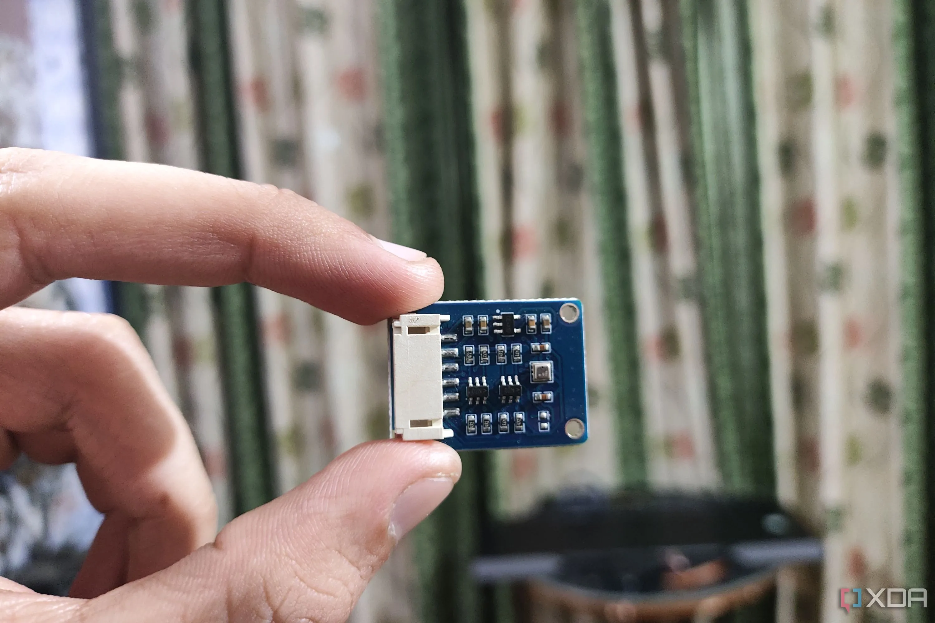 Một người đang cầm cảm biến BME280, dùng để đo nhiệt độ và độ ẩm phòng trong hệ thống nhà thông minh