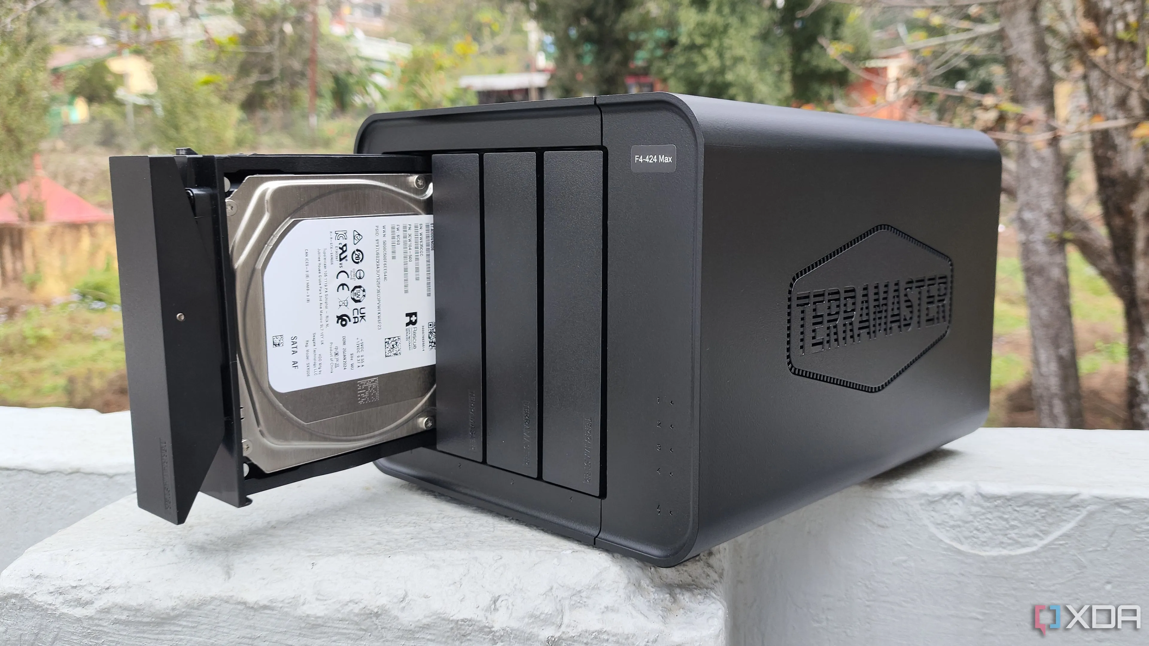 Một người đang cầm thiết bị NAS TerraMaster F4-424 Max, tượng trưng cho giải pháp lưu trữ media server hiệu quả với chi phí thấp bằng ổ cứng HDD