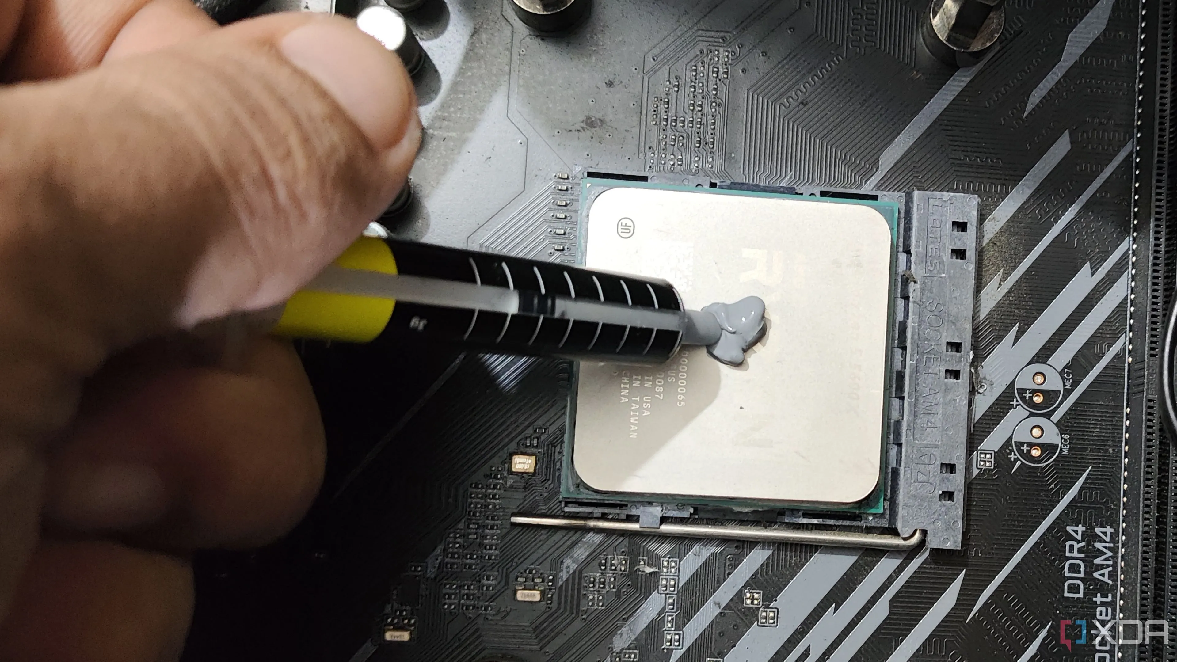 Một người đang thoa keo tản nhiệt lên bộ vi xử lý Ryzen 5 5600X, minh họa quá trình thay thế keo tản nhiệt cho CPU.