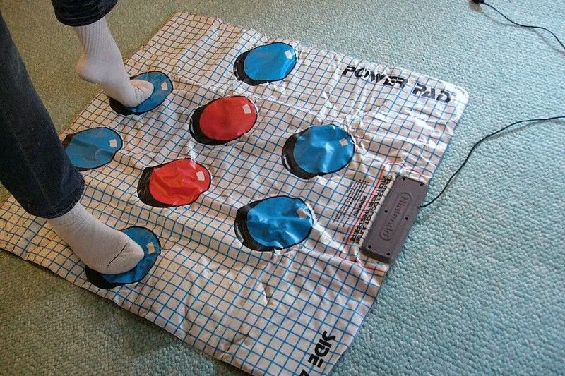 Người chơi đang đứng trên NES Power Pad màu xám, phụ kiện tập thể dục cho máy chơi game Nintendo Entertainment System