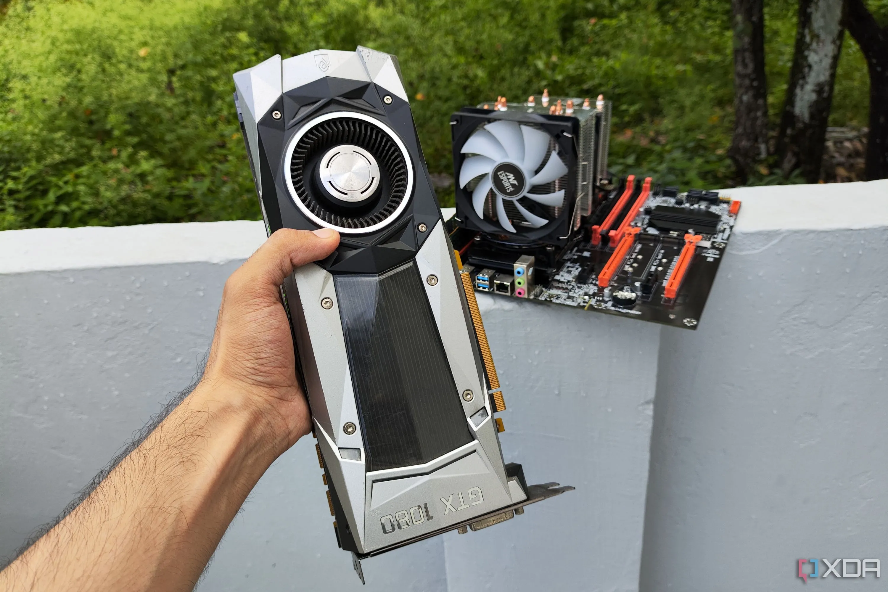 Người đang cầm card đồ họa GTX 1080 Founders Edition trước một thùng máy chủ Xeon cũ, minh họa việc nâng cấp PC chơi game giá rẻ.