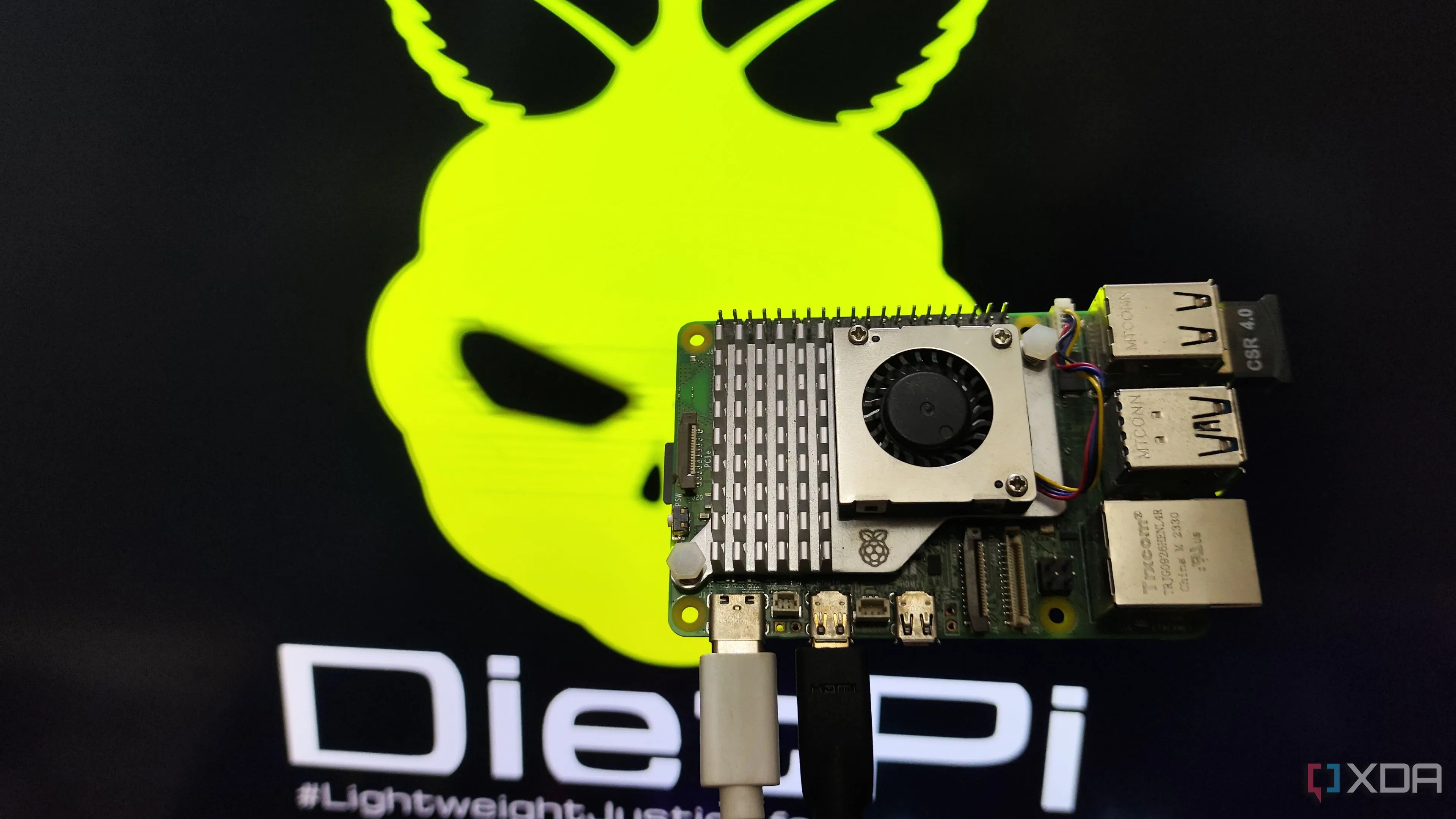 Người đang cầm Raspberry Pi 5 và màn hình hiển thị môi trường desktop DietPi LXDE, minh họa hệ điều hành DietPi nhẹ nhàng