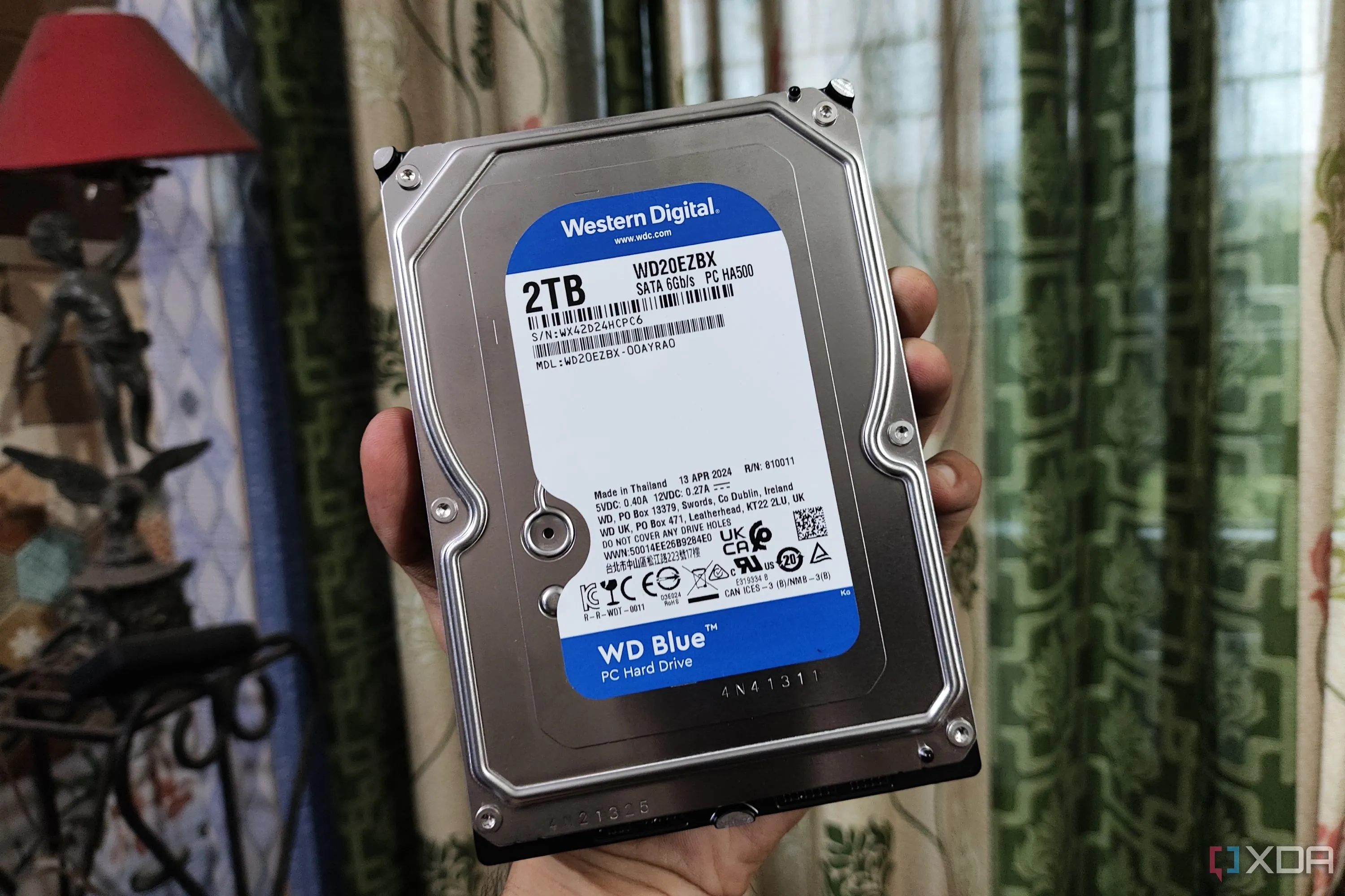 Người dùng đang cầm một ổ cứng HDD WD Blue 3.5 inch, biểu tượng cho giải pháp lưu trữ dữ liệu lớn trong NAS