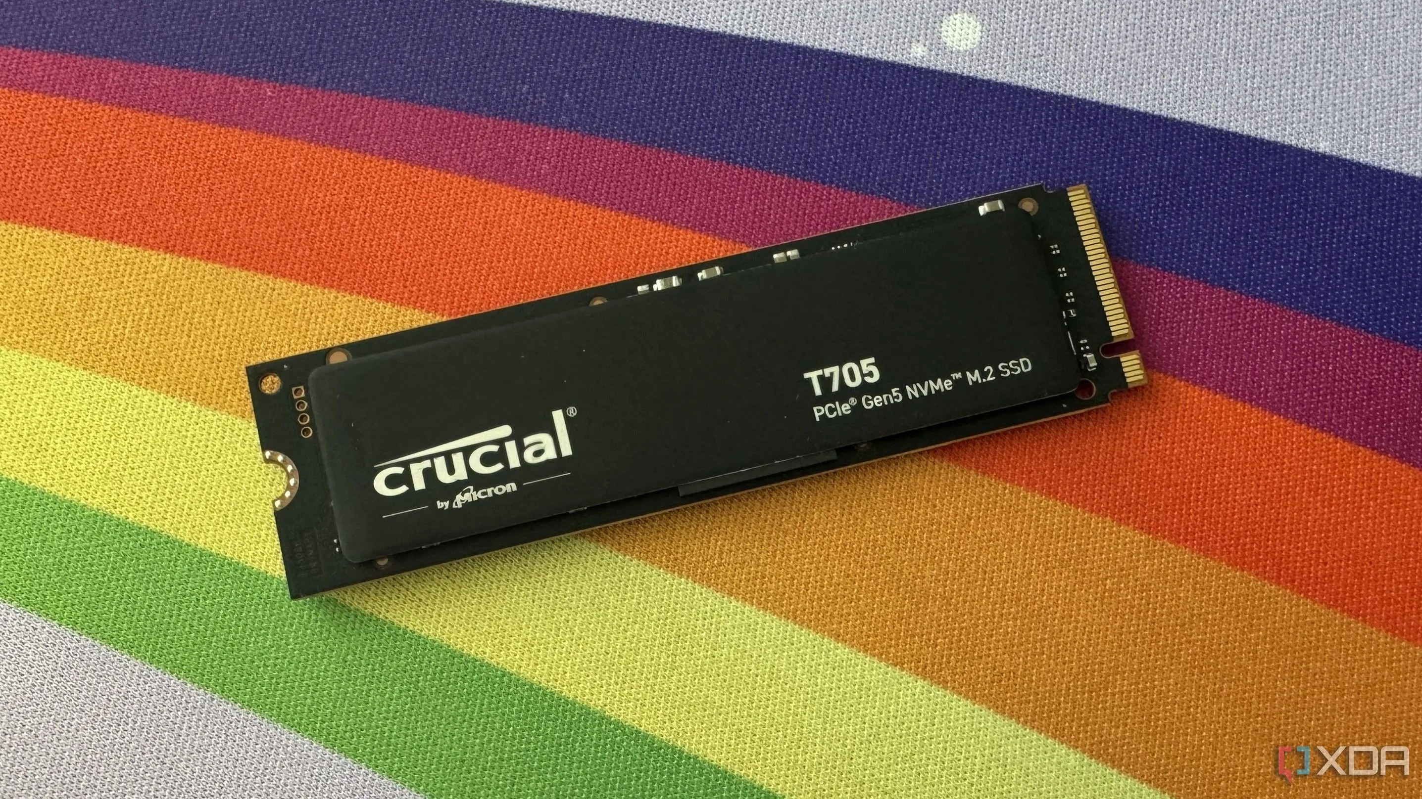 ổ cứng SSD Crucial T705 PCIe Gen5 đặt trên tấm lót bàn màu cầu vồng