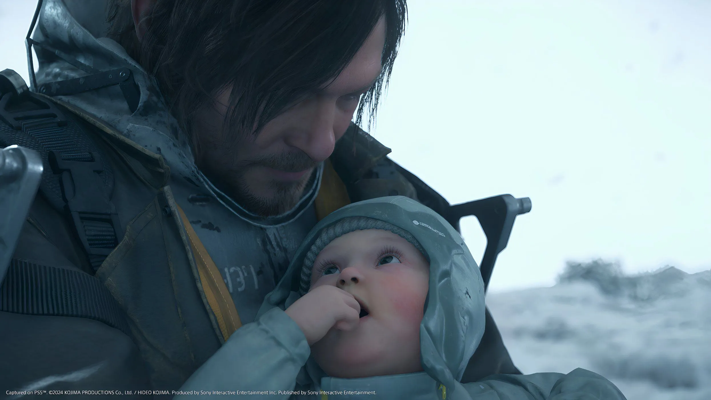 Sam Porter Bridges bế một em bé BB, đứng giữa cảnh hoang tàn trong Death Stranding 2: On The Beach, biểu tượng của sự sống sót và hy vọng