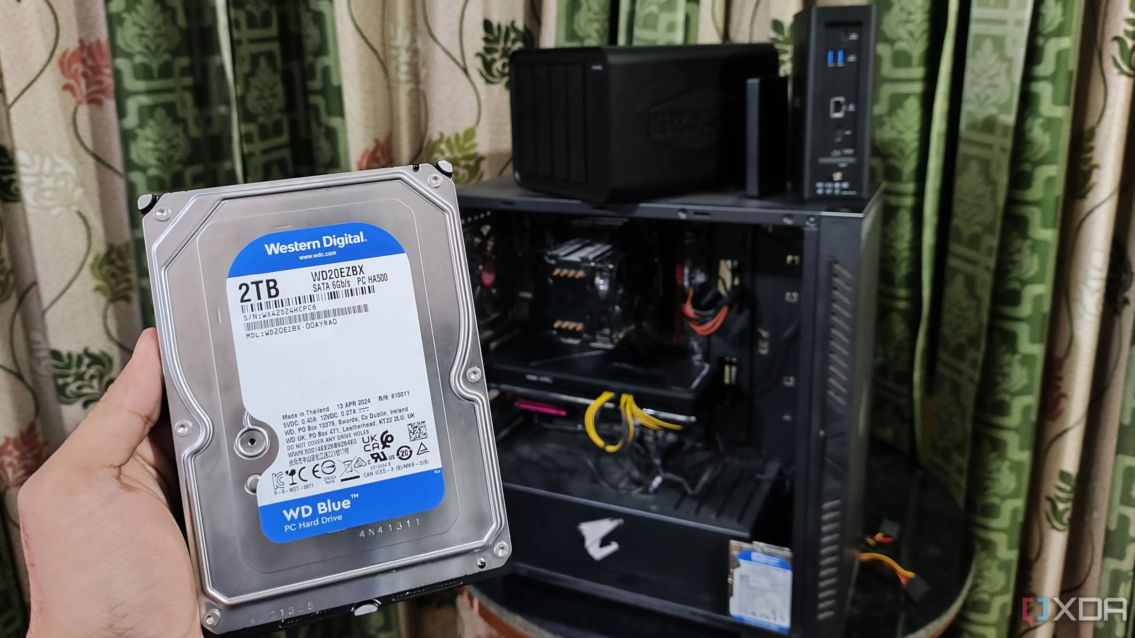 So sánh NAS tự lắp ráp và NAS thương mại với hình ảnh người cầm ổ cứng HDD và các thiết bị NAS TerraMaster.
