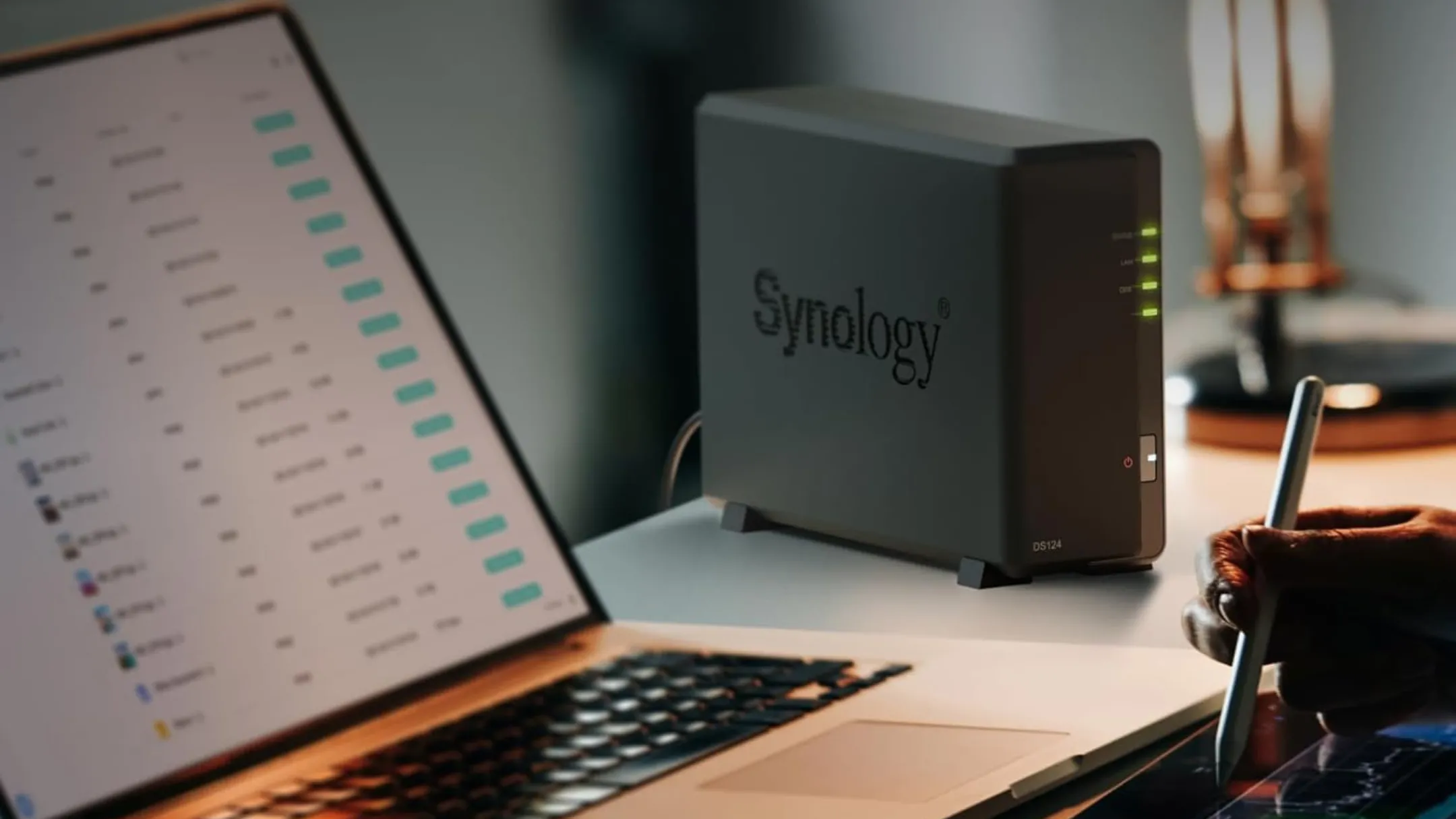 Synology DS124 đặt trên bàn làm việc cạnh laptop, minh họa khả năng lưu trữ tại nhà