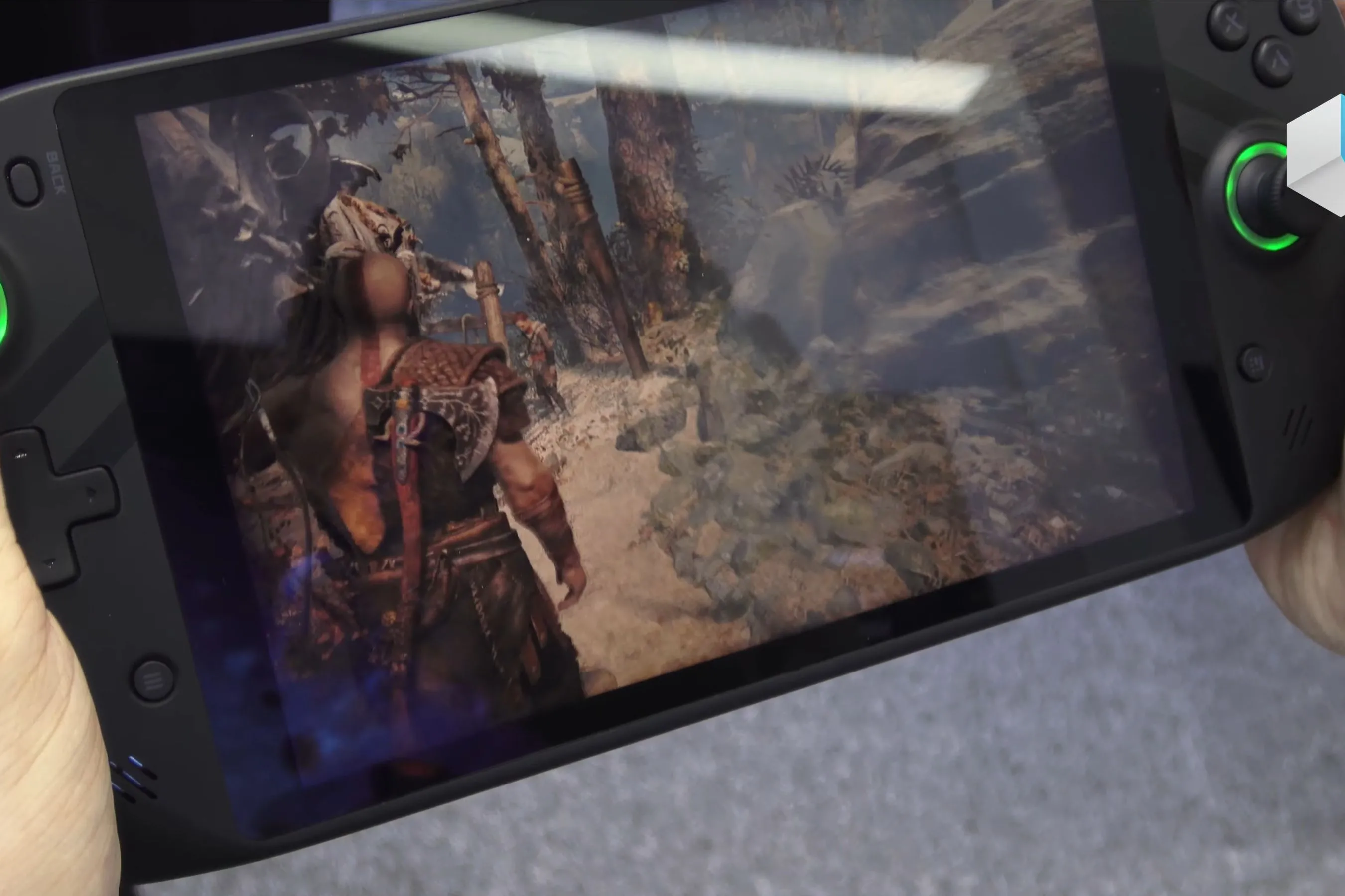 Thiết bị chơi game cầm tay hiển thị cảnh game God of War, Kratos và Atreus trong cuộc phiêu lưu